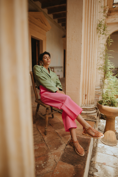 Model sitting in Mexican courtyard wearing Carmela fisherman sandals handmade in Mexico.